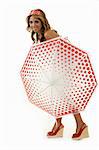 Full body of a beautiful blond hair woman standing behind a red and white polka dot umbrella with matching headband on white