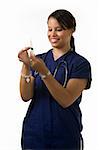 Young attractive African American  woman healthcare worker wearing dark blue scrubs and a stethoscope holding and looking at a syringe with a friendly smile