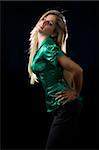 beautiful young woman with blond hair wearing shiny green satin blouse posing on black background