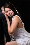 beautiful brown hair woman wearing white dress sitting on a black chair on black background