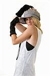 Cute blond hair young woman wearing funky hat and arm coverings for a funky style posing sideways with arms on head standing on white