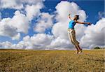 Beautiful woman jumping on a golden meadow