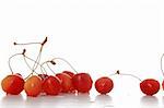 some cherries laying randomly on a table, white background