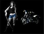 Attractive sexy woman in shorts holding a samurai sword standing beside a harley motorcycle on black