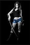 Attractive sexy woman in shorts holding a samurai sword standing on black