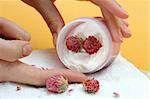 Spa essentials (cream, white towel and flowers) isolated on yellow