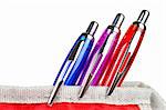 Three pens in a red pencil case over a white background