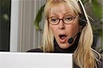 Attractive businesswoman galks in surprise while on her phone headset.