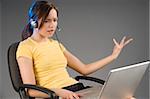 girl sitting with the laptop on her legs and talking vividly at computer