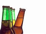 A delicious cold beer peeking from behind green bottles.