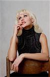 blondie in black dress sitting on a chair, portrait, white background