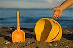 Beach toys and child's hand by the sea shore