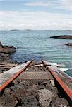 A train track runs from a boat shed into the water of the Hauraki Gulf