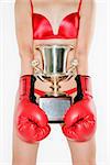 Torso of Caucasian  woman wearing  lingerie holding a trophy with boxing gloves.