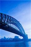 Low angle view of Sydney Harbour Bridge in Australia with view of harbour and downtown skyline.