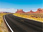 Curve in road in scenic desert road with mesa land formations and mountains.