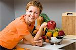 Beautiful woman with apple and fresh fruits in the kitchen