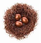 Three eggs in a nest of bronze colour on a white background