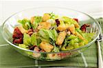 Fresh caesar salad with croutons and bacon bits served in a glass bowl