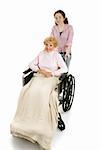 Teen girl pushing a disabled senior woman in a wheelchair.  Isolated on white.