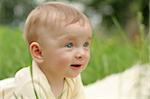 Cute small boy in green grass - he smiles and has fun