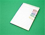 open notebook with several paper clips over a green surface