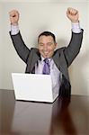 Happy businessman looks at his success on his laptop.