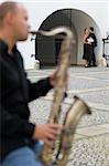 A street musician playing his saxophone serenades two young lovers