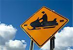 Snowmobile sign against colorful blue sky with clouds