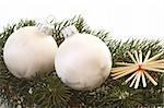 Two white christmas tree balls on a fir branch