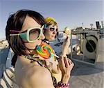 Fisheye shot of girls in brightly colored clothing on a roof with sunglasses and lollipops