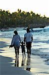 Family taking a walk on a sandy beach of tropical resort