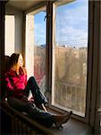 Beauty red-hair girl sitting on window. Thinking and may be dreaming