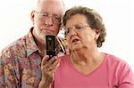 Senior Couple looks at the screen of a cell phone.