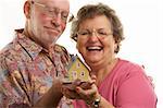 Happy Senior Couple holding a model home.