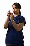 Young attractive African American  woman healthcare worker wearing dark blue scrubs and a stethoscope holding and looking at a syringe