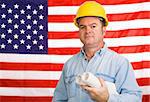 Construction worker with blueprints in front of an American flag.  Photographed in front of the flag, not a composite image.