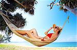 view of nice woman lounging in hammock in tropical environment