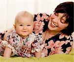 The smiling girl in dress with laughing mum on bed