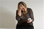 Older female patient with her hand on her head looking down at a blood pressure device on her wrist