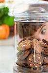 little girl looking at cookies in a jar