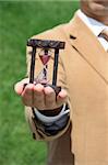 A business man holding a wooden hourglass on his hand