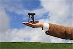 A business man holding a wooden hourglass