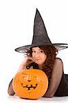Portrait of Hispanic teenager girl in black Halloween hat and fishnet dress with carved pumpkin (Jack O' Lantern)