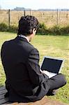 A young businessman working on a laptop in a rural property