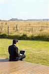 A young businessman working on a laptop in a rural property