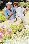 Grandfather and grandson outdoors in garden talking and smiling