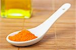 Saffron in the spoon and oil bottle for prepare tasty food with soft shadow in the bamboo mat background. Shallow depth of field