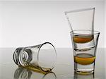 Three shots of whiskey on white background over gray floor.