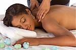 Beautiful young black female is relaxing while being massaged in spa